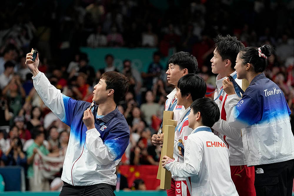 | Photo: AP/Petros Giannakouris : South Korea's Lim Jonghoon, left, takes a selfie with North Korea's Ri Jong-sik and others during medal ceremony